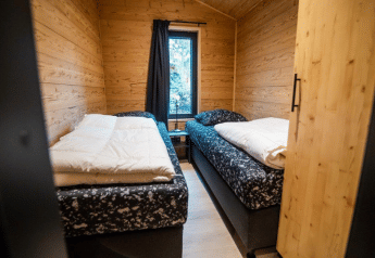 Chambre accueillante avec deux lits simples au Terrace Chalet de Bospark Markelo, Pays-Bas, murs en bois.
