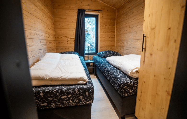 Acogedor dormitorio con dos camas en Terrace Chalet de Bospark Markelo, Países Bajos, paredes de madera.