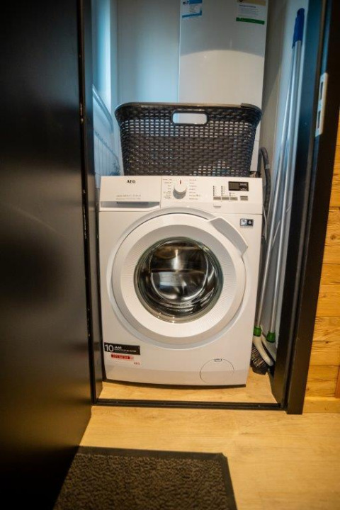 Waschmaschine in einem kleinen Schrank mit Korb darüber, fotografiert in der Terrace Chalet in Bospark Markelo.