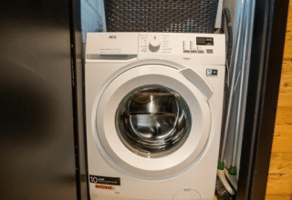 Washing machine in a closet with a laundry basket on top, at Terrace Chalet in Bospark Markelo, Netherlands.