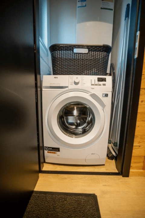 Washing machine in a closet with a laundry basket on top, at Terrace Chalet in Bospark Markelo, Netherlands.