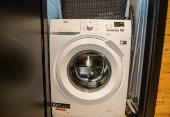Washing machine in a closet with a laundry basket on top, at Terrace Chalet in Bospark Markelo, Netherlands.