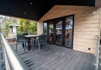 Terrazza esterna con tavolo e sedie al Terrace Chalet, Bospark Markelo, Paesi Bassi, circondata da alberi.