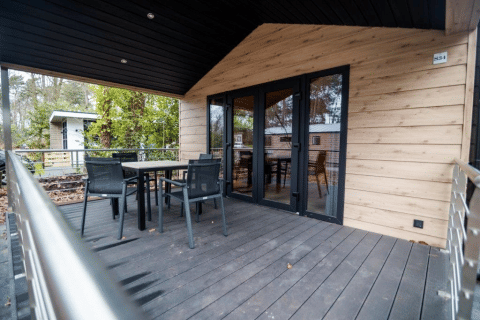 Terrazza esterna con tavolo e sedie al Terrace Chalet, Bospark Markelo, Paesi Bassi, circondata da alberi.