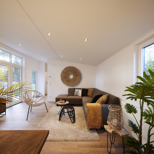 Modernes Wohnzimmer in der Cubus Lodge im Bospark Markelo, Niederlande, mit stilvoller Einrichtung und Pflanzen.