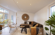 Moderne woonkamer in Cubus Lodge van Bospark Markelo, Nederland, met warme inrichting, planten en veel licht.