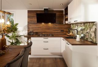 Interno cucina moderna nella Cubus Lodge al Bospark Markelo, Paesi Bassi, con accenti di legno e bianco.