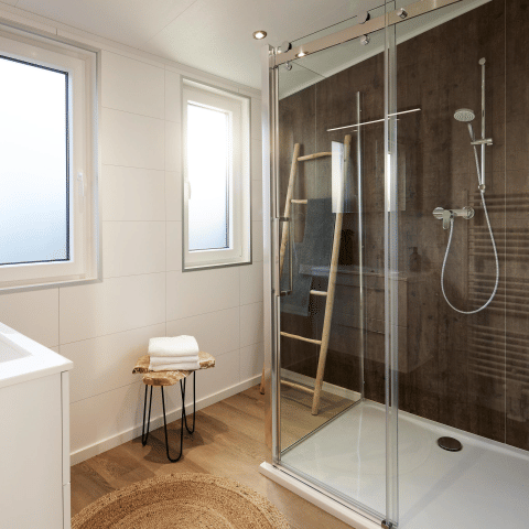 Bagno moderno con doccia in vetro, parete in legno, finestre e stile minimalista al Cubus Lodge.