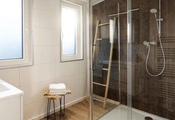 Bagno moderno con doccia in vetro, parete in legno, finestre e stile minimalista al Cubus Lodge.