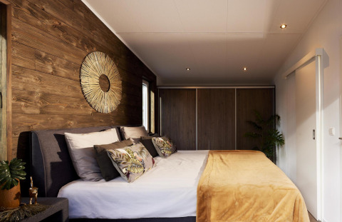 Dormitorio moderno en Cubus Lodge, Bospark Markelo, Países Bajos, con paredes de madera y decoración acogedora.