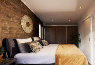Dormitorio moderno en Cubus Lodge, Bospark Markelo, Países Bajos, con paredes de madera y decoración acogedora.