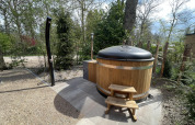 Bain à remous rond en bois avec couvercle et escaliers à l’extérieur d’un lodge à De Utrechtse Heuvelrug, Pays-Bas.