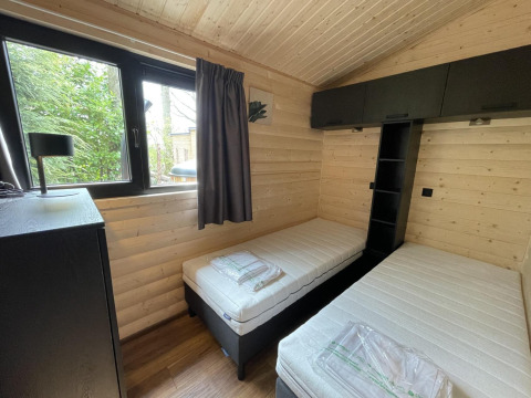 Dormitorio moderno con dos camas individuales, paredes de madera y ventana en Hackfort Wood Hottub 6, De Utrechtse Heuvelrug.