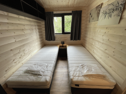 Deux lits simples dans une chambre en bois chaleureuse à Hackfort Wood Hottub 6, De Utrechtse Heuvelrug, Pays-Bas.