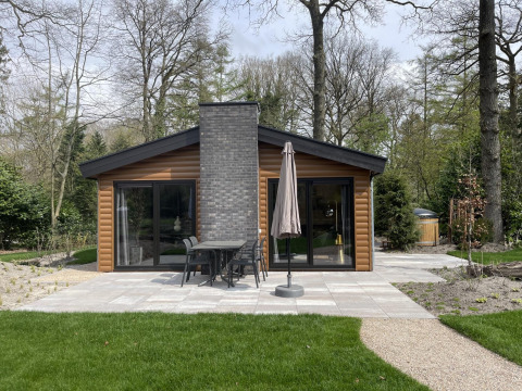 View of Hackfort Wood Hottub 6 lodge at De Utrechtse Heuvelrug, Netherlands, surrounded by trees and nature.