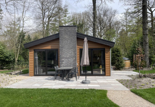 Blick auf die Hackfort Wood Hottub 6-Lodge bei De Utrechtse Heuvelrug, Niederlande, umgeben von Wald.
