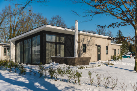 Bos Lodge au Holiday Resort 't Schuttenbelt aux Pays-Bas, lodge moderne avec grande baie vitrée sous la neige.