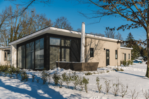 Bos Lodge ved Holiday Resort 't Schuttenbelt i Holland, moderne hytte med store vinduer omgivet af sne.