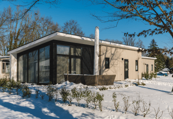Bos Lodge im Ferienpark 't Schuttenbelt, Niederlande, moderne Unterkunft mit Panoramafenstern im Schnee.