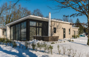 Bos Lodge bij Holiday Resort 't Schuttenbelt in Nederland, moderne lodge met grote ramen en besneeuwde tuin.