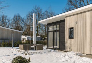 Moderne Bos Lodge bij Holiday Resort 't Schuttenbelt in Nederland, omgeven door sneeuw en winterse sfeer.
