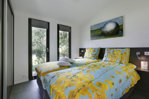 Dormitorio en Bos Lodge del Holiday Resort 't Schuttenbelt en Países Bajos, con grandes ventanas y decoración moderna.