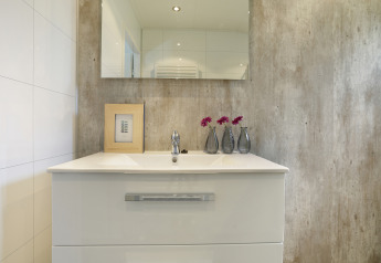 Modern bathroom sink, mirror, framed picture, and vases with flowers at Bos Lodge, 't Schuttenbelt.