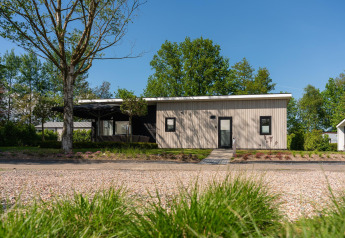 Lodge Forest moderne avec sauna et jacuzzi privés au Holiday Resort 't Schuttenbelt, Pays-Bas, entouré de verdure.