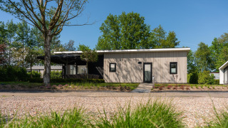 Lodge Forest moderne avec sauna et jacuzzi privés au Holiday Resort 't Schuttenbelt, Pays-Bas, entouré de verdure.