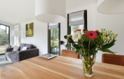 Bright lodge interior with flower bouquet on table, sofa and large windows, Forest lodge Netherlands.