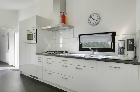 Cucina moderna nella Forest Lodge con mobili bianchi, piano cottura a gas e macchina da caffè nel resort.