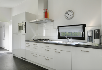 Cucina moderna nella Forest Lodge con mobili bianchi, piano cottura a gas e macchina da caffè nel resort.