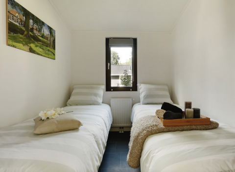 Due letti singoli in una camera accogliente e moderna al Forest Lodge nei Paesi Bassi.