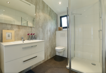Salle de bain moderne avec douche, WC suspendu et lavabo à la Forest Lodge du Holiday Resort 't Schuttenbelt, Pays-Bas.