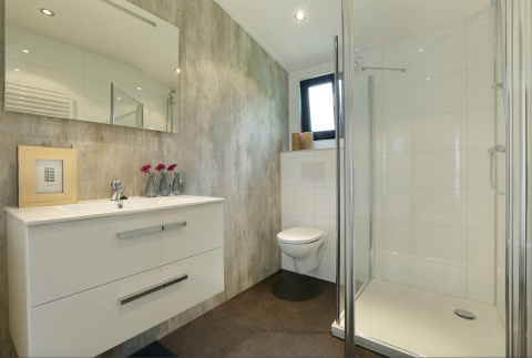 Modernes Bad mit Dusche, Wandtoilette und Waschtisch in der Forest Lodge im Holiday Resort 't Schuttenbelt.