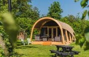 Tienda de safari Tent lodge XL con instalaciones sanitarias en Holiday Resort 't Schuttenbelt, Países Bajos, rodeada de vegetación.