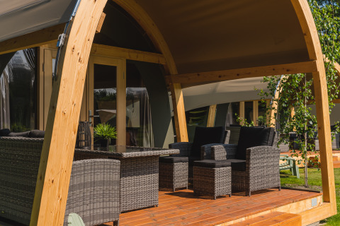 Covered patio with wicker furniture outside a spacious safari tent at Holiday Resort 't Schuttenbelt, Netherlands.