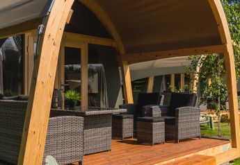 Terrasse couverte avec des meubles en osier devant une tente safari au Holiday Resort 't Schuttenbelt, Pays-Bas.
