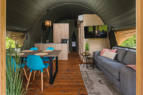 Binnenzicht van een luxe safaritent met leef- en eetruimte in Holiday Resort 't Schuttenbelt, Nederland.