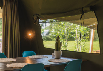 Intérieur d'une tente safari avec table à manger, chaises et cactus au Holiday Resort 't Schuttenbelt, Pays-Bas.