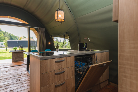 Kitchen area inside a Tent Lodge XL safari tent with open dishwasher at Holiday Resort 't Schuttenbelt, Netherlands.
