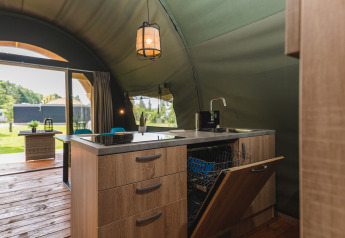 Küchenbereich im Safari-Zelt Lodge XL mit offener Spülmaschine im Holiday Resort 't Schuttenbelt, Niederlande.