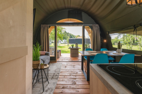 Vista interior de la tienda safari XL con comedor moderno, sala acogedora y acceso a la terraza exterior.