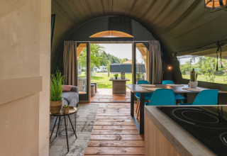 Vista interior de la tienda safari XL con comedor moderno, sala acogedora y acceso a la terraza exterior.