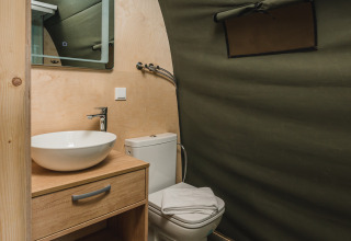 Bagno moderno in tenda safari con lavandino, specchio e wc presso Holiday Resort 't Schuttenbelt, Paesi Bassi.