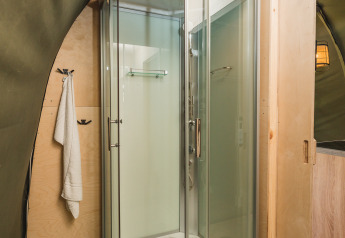 Cabina doccia moderna in vetro all'interno di una tenda safari XL con bagno privato a 't Schuttenbelt, Paesi Bassi.