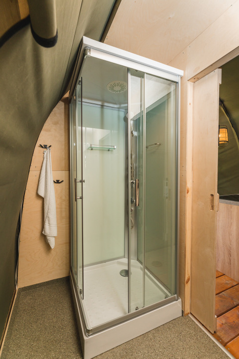 Cabine de douche moderne en verre dans une tente safari XL avec sanitaire au Holiday Resort 't Schuttenbelt, Pays-Bas.