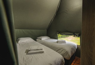 Due letti singoli con lenzuola bianche in una tenda safari con finestra al Holiday Resort 't Schuttenbelt, Paesi Bassi.
