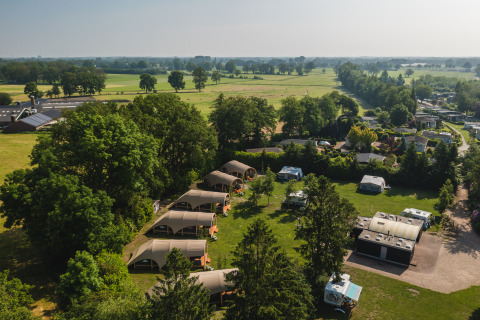Vista aérea de tiendas safari y autocaravanas en el Holiday Resort 't Schuttenbelt en Países Bajos, rodeado de naturaleza.