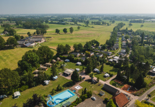 Aerial view of Safari Tent Lodge XL with pool and lush fields at Holiday Resort 't Schuttenbelt, Netherlands.